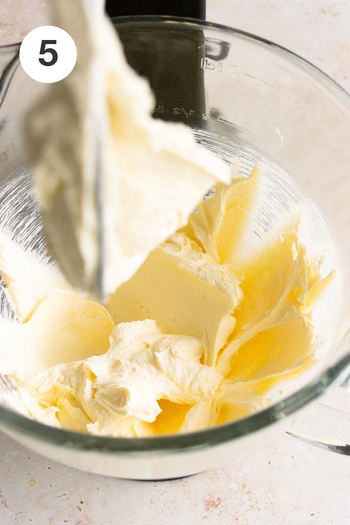 Creamed butter and sugar mixture in the glass bowl of a stand mixer.