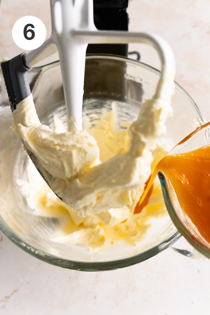 The wet mixture being added to the creamed butter and sugar mixture in the glass mixing bowl of a stand mixer.