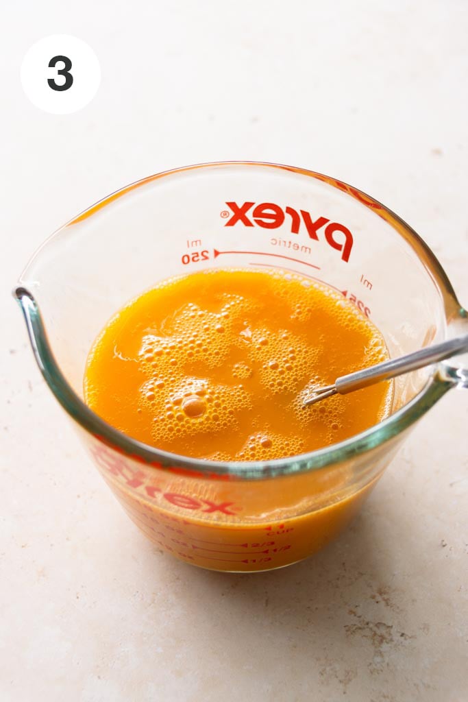 Pound cake recipe step: Wet mixture of eggs, egg yolks, vanilla extract and salt in a glass measuring cup.